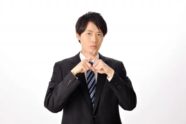 バツ印を作る男性